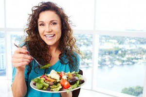 Beautiful happy female eating a salad